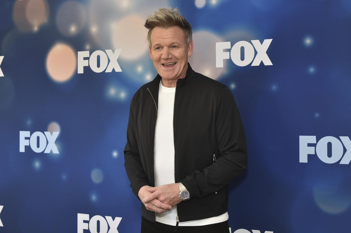 Gordon Ramsay smiling in a black windbreaker over a white T-shirt while arriving at a TV network event