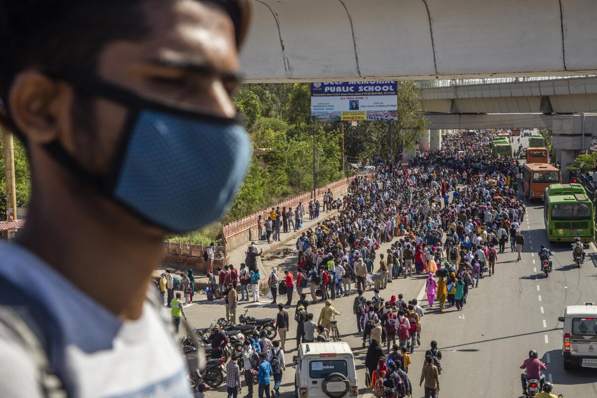 In India, crowds of migrant workers wait to board buses to return to native villages.