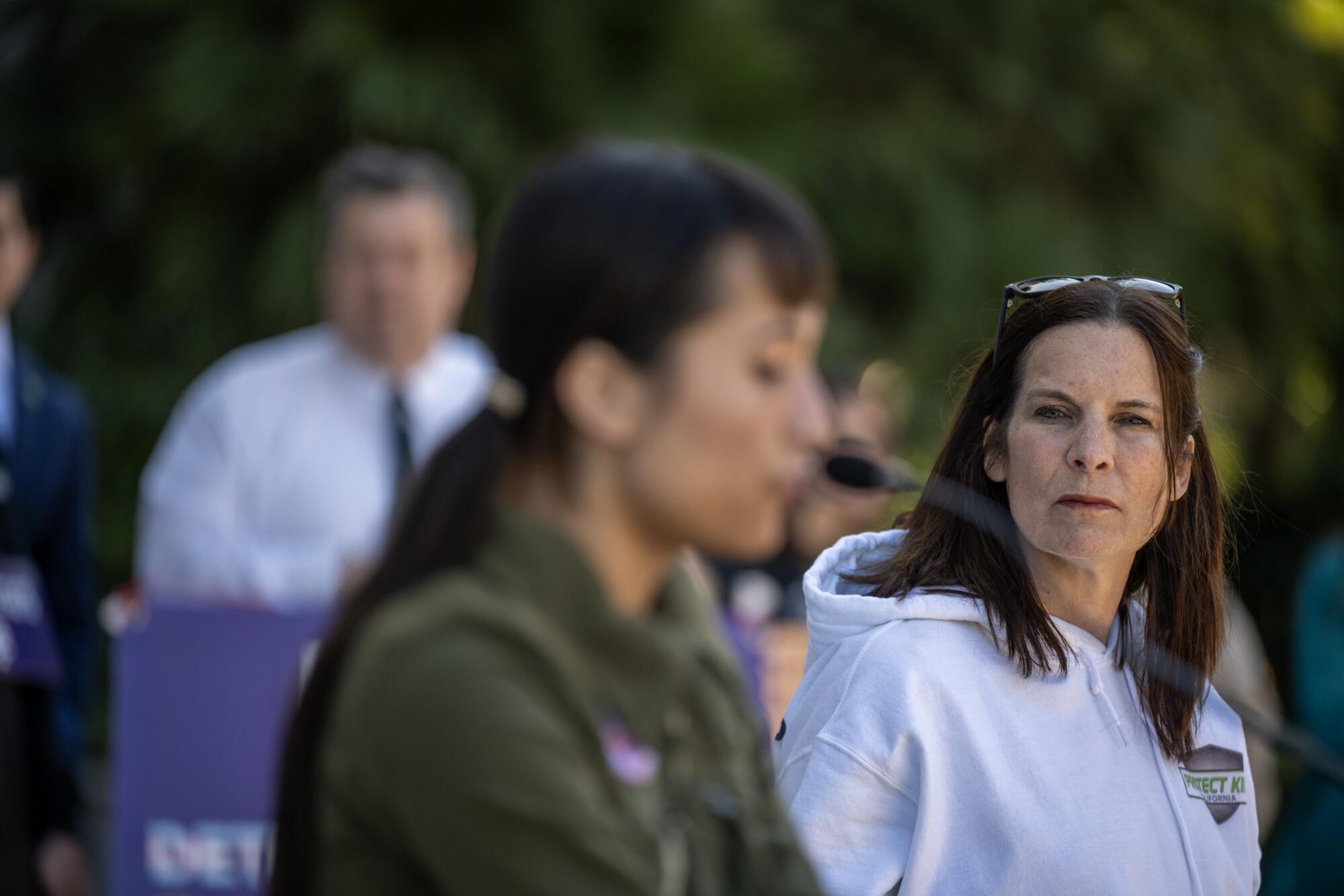 Erin Friday listens to Chloe Cole addresses a small crowd on the west steps of the state capitol.