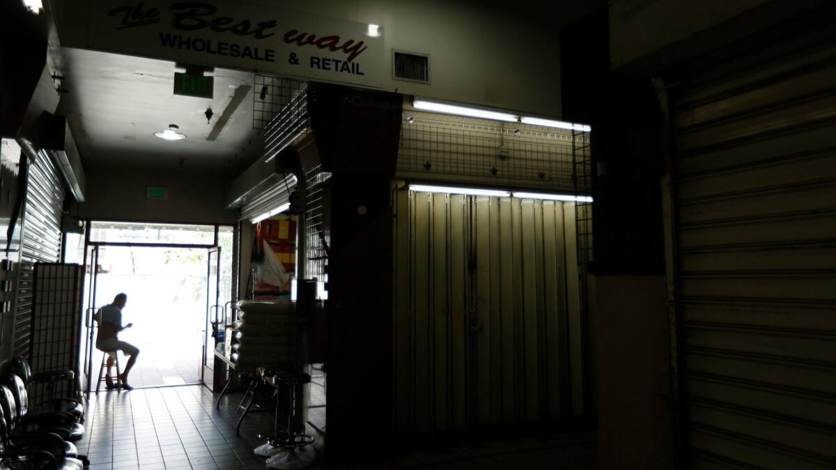 A lone person sits in a doorway next to stalls that are closed at the swap meets in Chinatown.