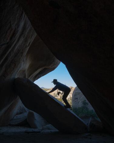 Looking out from a cave decorated with ancient art toward its opening and the blue sky beyond