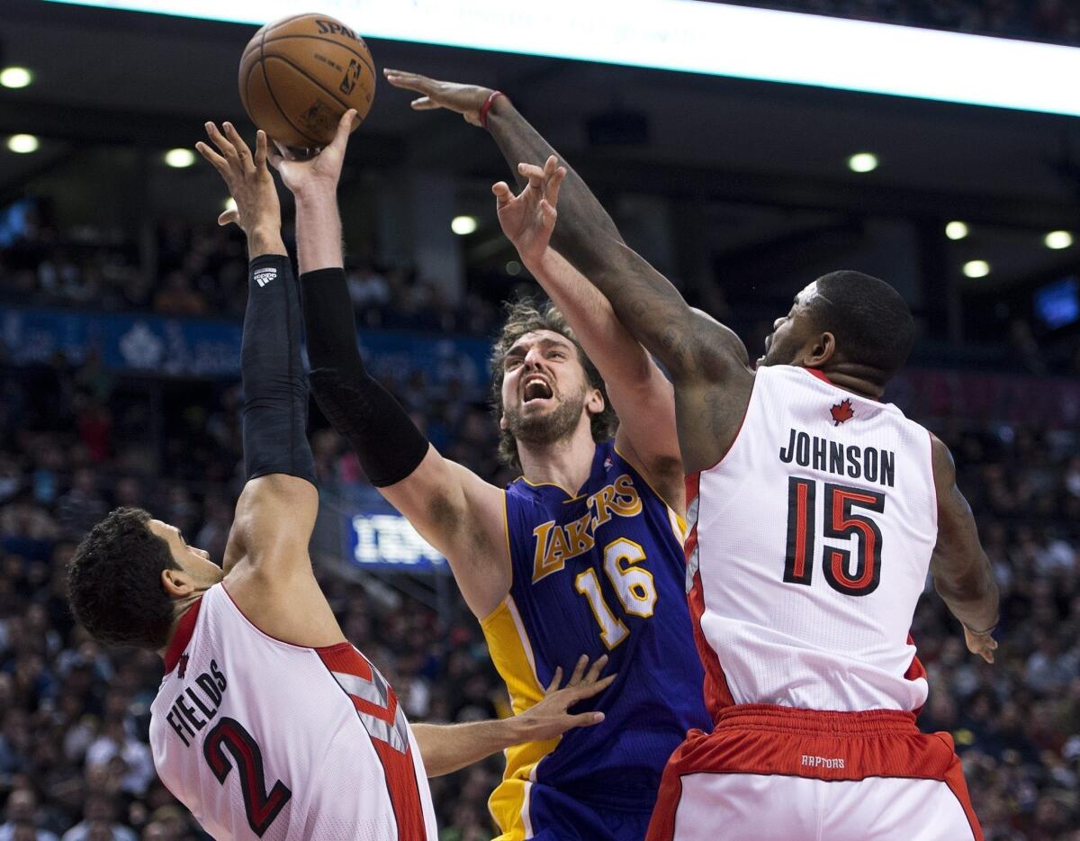 Lakers power forward Pau Gasol has his shot challenged by Raptors center Amir Johnson and forward Landy Fields in the second half.