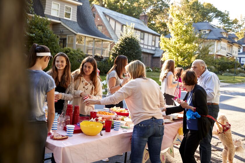 Neighbors chat around a table at a block party.