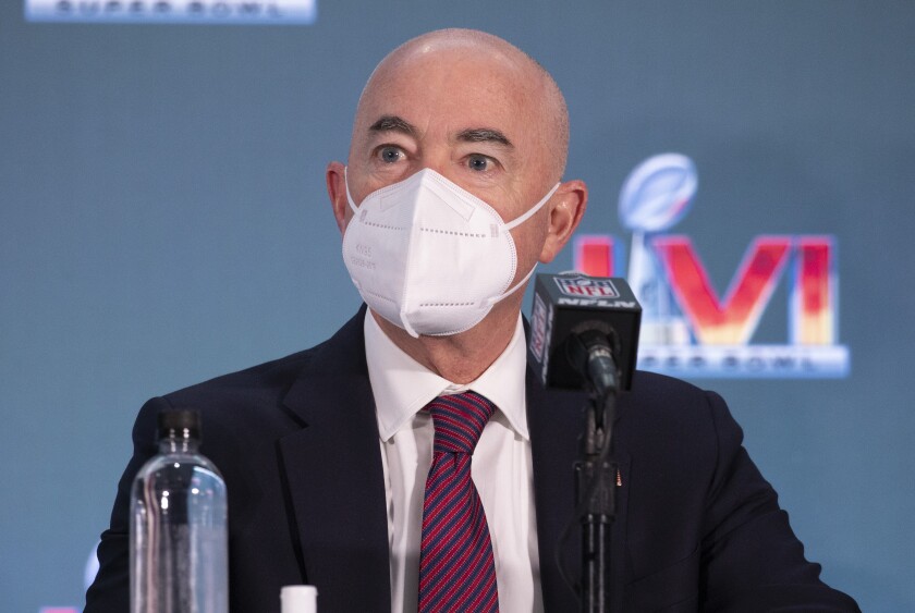 Alejandro Mayorkas wears a mask while sitting and speaking into a microphone
