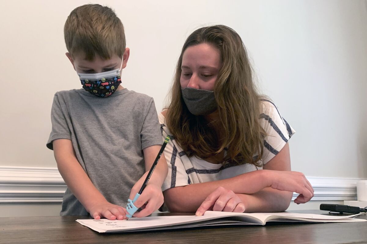 Emily Goss goes over school work at the kitchen table with her five-year-old son inside their Monroe, N.C., home on Monday, Sept. 13, 2021. The Goss' have decided to homeschool Berkeley after the Union County school district chose not to implement a mask mandate for children. (AP Photo/Sarah Blake Morgan)