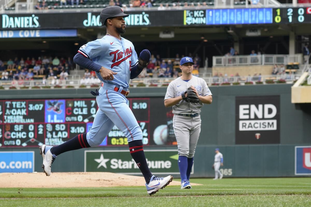 Minnesota Twins' Byron Buxton, left, jogs home on a sacrifice fly by Luis Arraez off Kansas City Royals pitcher Kris Bubic, right, in the first inning of a baseball game, Sunday, Sept. 12, 2021, in Minneapolis. (AP Photo/Jim Mone)
