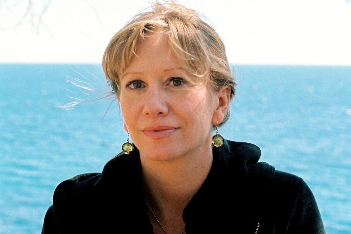 Translator Megan McDowell, wearing a black hoodie, with the ocean behind her