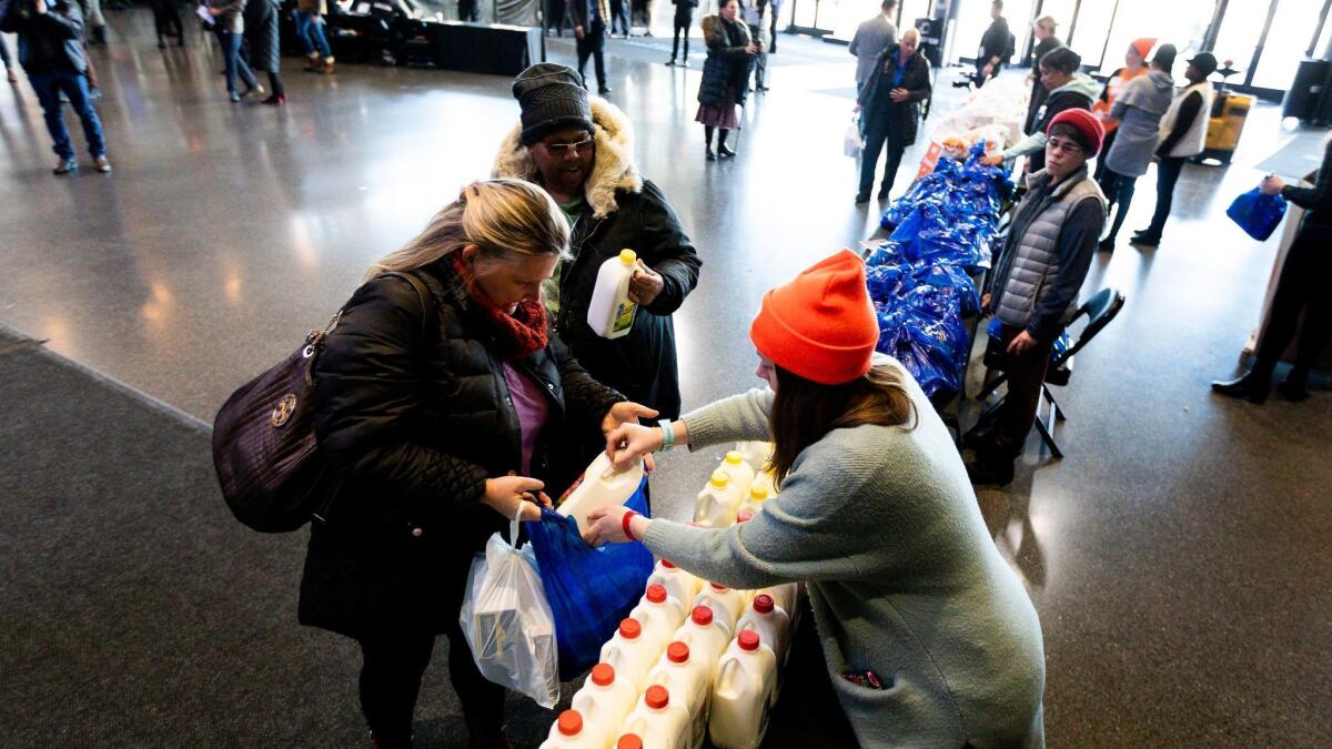 Unpaid federal workers collect collect milk and food at a food donation site set up by the Food Bank of NYC at the Barclays Center in Brooklyn, N.Y.