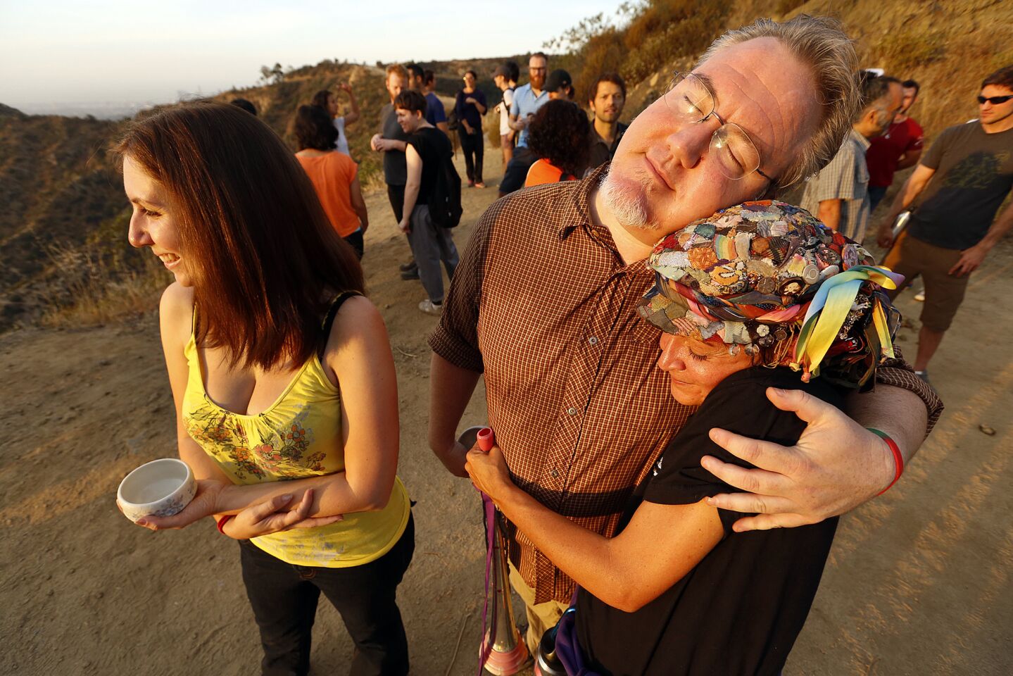 Jonathan Reilly hugs the Teafaerie, right, as Lauren DeAngelus, left, takes in the sunrise. For a brief moment, a motley crew of Angelenos was brought together by art and tea.