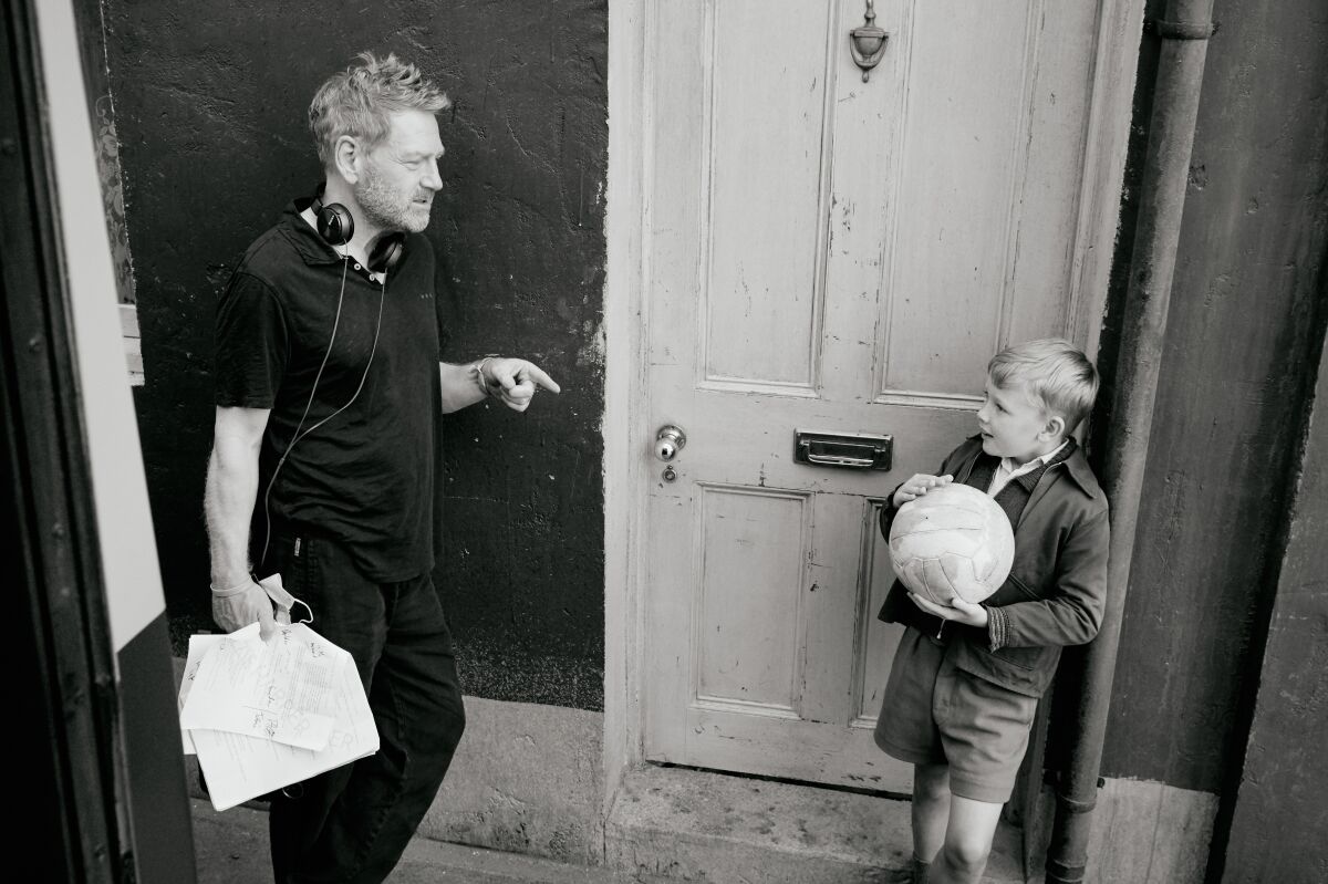 A man talks to a young boy holding a ball. 