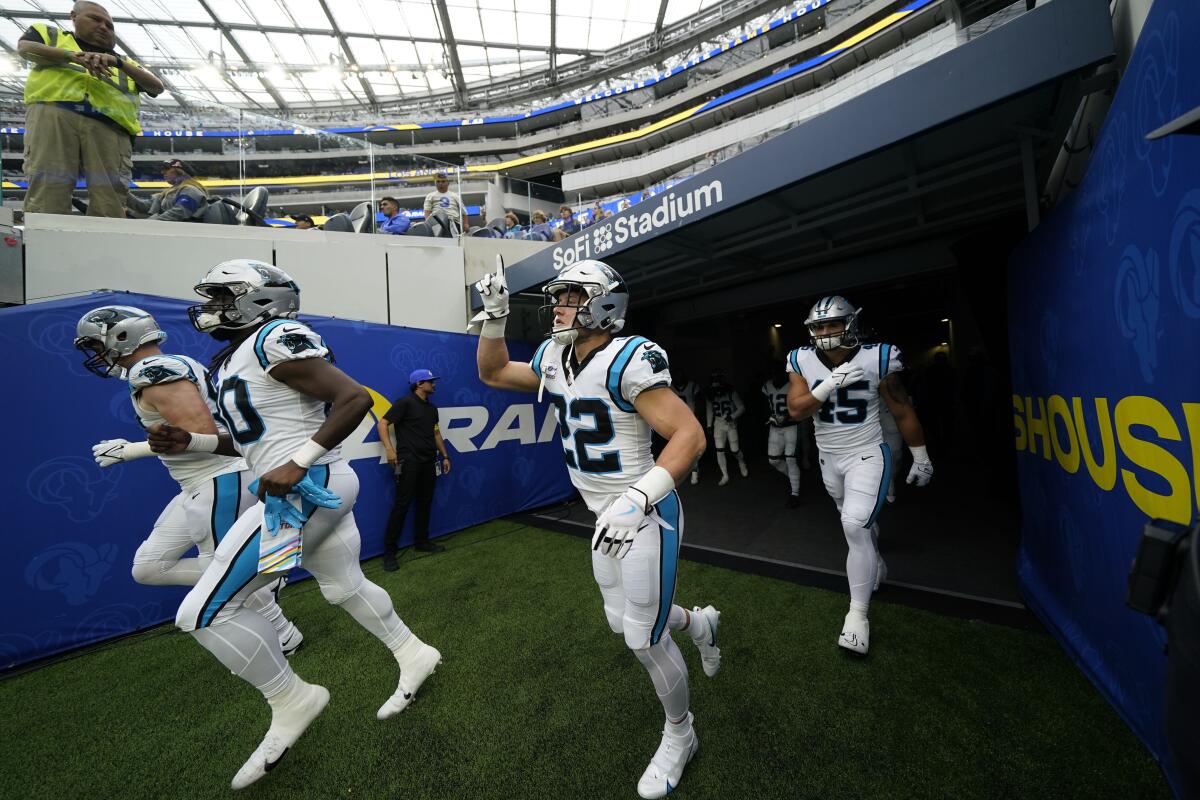 Carolina Panthers running back Christian McCaffrey runs onto the field with his teammates.