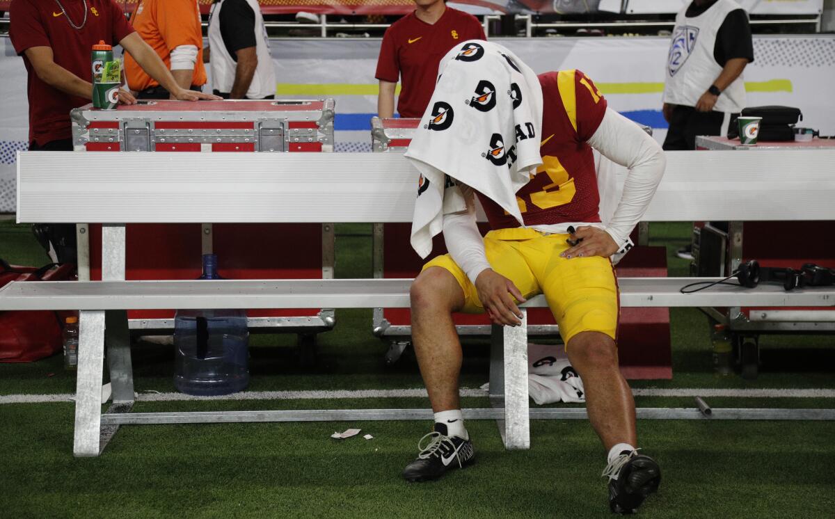 USC quarterback Caleb Williams sits on the bench with a towel over his head after the Trojans' 47-24 loss to Utah.