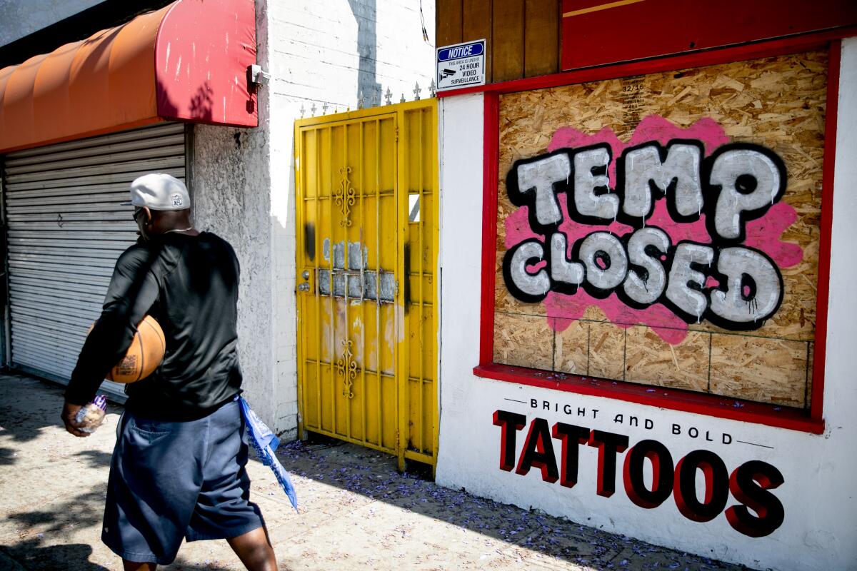 A tattoo parlor on El Cajon Boulevard has its windows boarded up on May 28, 2020.