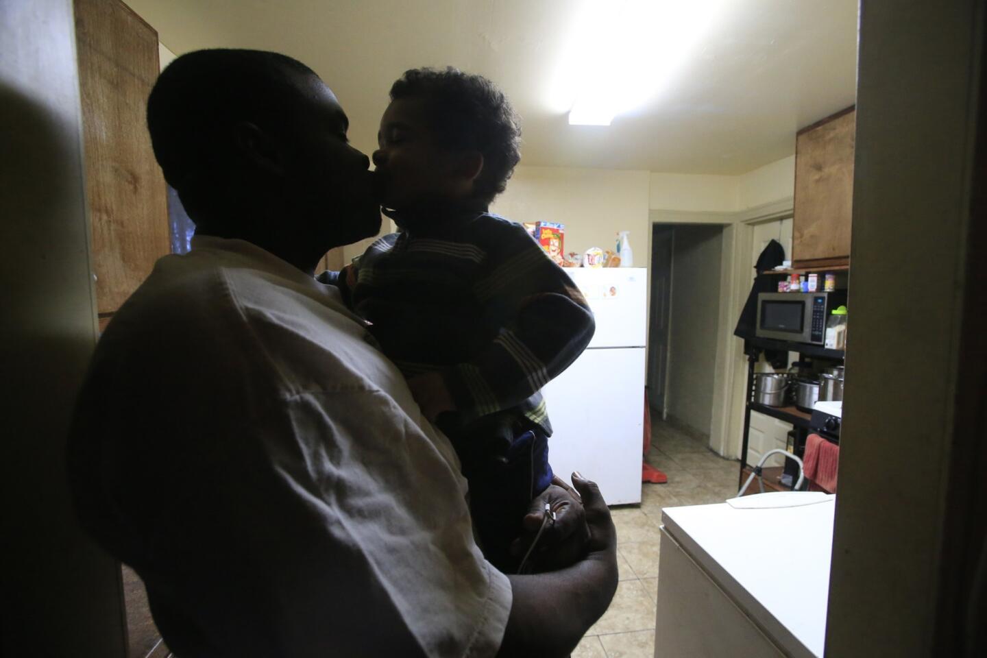 Shortly after sunrise, Bryan August-Jones gives his youngest son, Jonathan, a kiss in the kitchen of their Watts home. August-Jones wakes before dawn each weekday to get his his three sons ready for school and the baby-sitter.