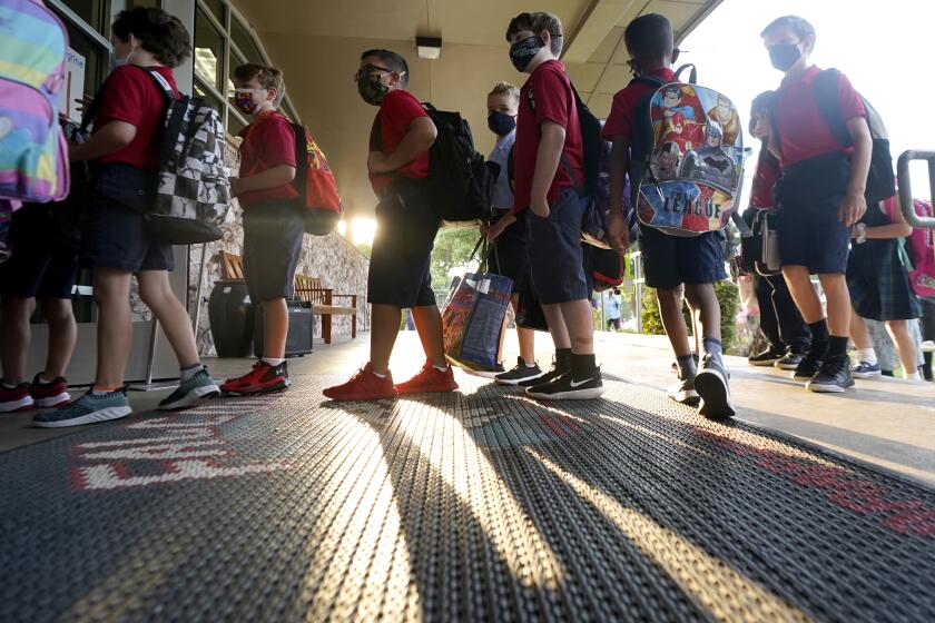 Wearing masks to prevent the spread of COVID-19, elementary school students line up to enter school for the first day of classes in Richardson, Texas, Tuesday, Aug. 17, 2021. Despite Texas Gov Greg Abbott's executive order banning mask mandates by local officials, the Richardson Independent School District and many others across the state are requiring masks for students. (AP Photo/LM Otero)