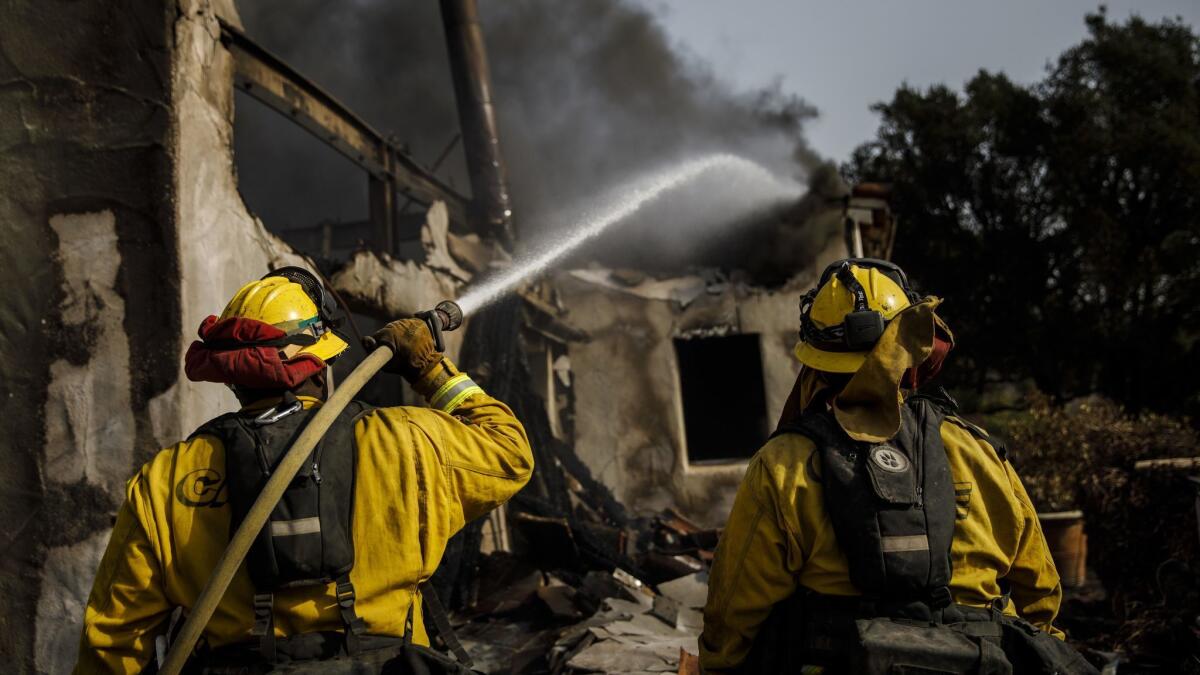 Humboldt County firefighters hoses down smoldering flames inside a destroyed home after the Thomas Fire burned in Montecito, Calif. in December 2017.