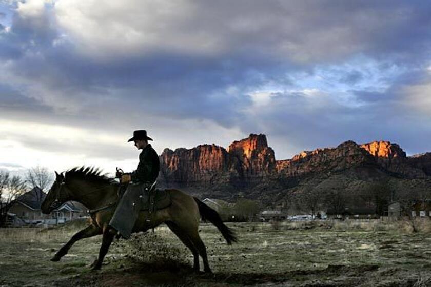 A young man claiming to be a local town security guard rides through an empty lot at sunset in Colorado City, Ariz.