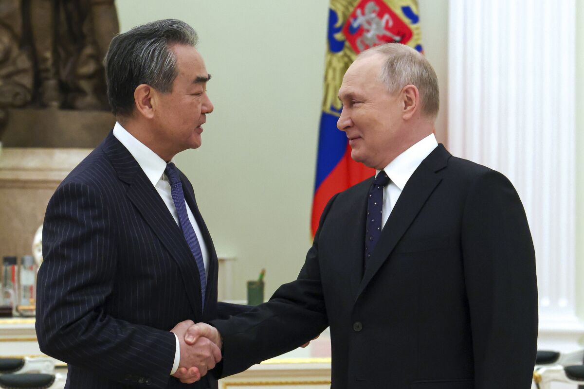 Russian President Vladimir Putin and Chinese foreign policy chief Wang Yi shaking hands