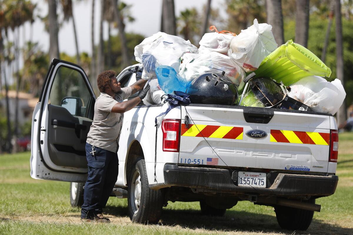 City of San Diego Park and Recreation worker Jaril Pargo cleans up trash in Mission Bay Park on Monday, July 5, 2021.