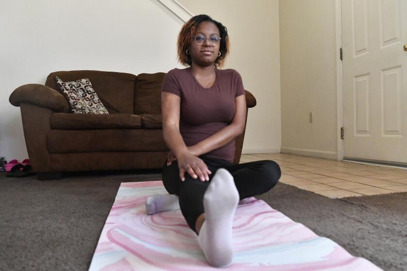 Jalen Matthews stretches on her yoga mat in her home in Louisville, Ky., Monday, Dec. 4, 2023. She was diagnosed with sickle cell at birth and had her first pain crisis at age 9. Three years later, the disease led to a spinal cord stroke that left her with some paralysis in her left arm and leg. “I had to learn how to walk again, feed myself, clothe myself, basically learn how to do everything all over again,” said Matthews, who is now 26. (AP Photo/Timothy D. Easley)