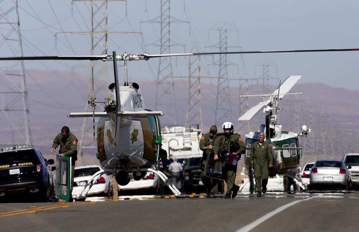 Law enforcement helicopters line Highway 395 between Kramer Junction and Ridgecrest after a suspect who allegedly opened fire on passersby during an hourlong police pursuit in Central California was killed and two people found with bullet wounds in the trunk of his vehicle were airlifted to an area hospital.