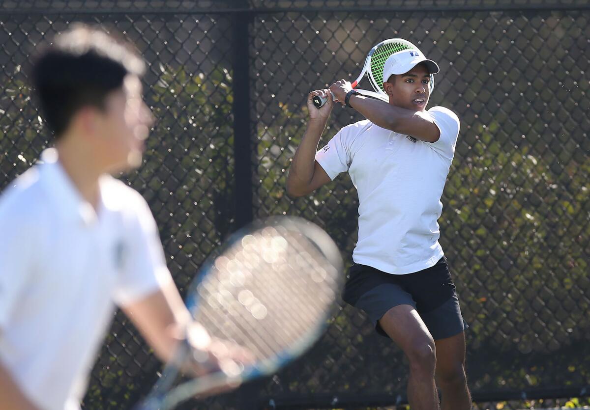 Sage Hill doubles player Rohun Krishnan, right, rips a backhand return as partner Brian Yu watches in a season opener against Newport Harbor on Tuesday in Newport Beach.