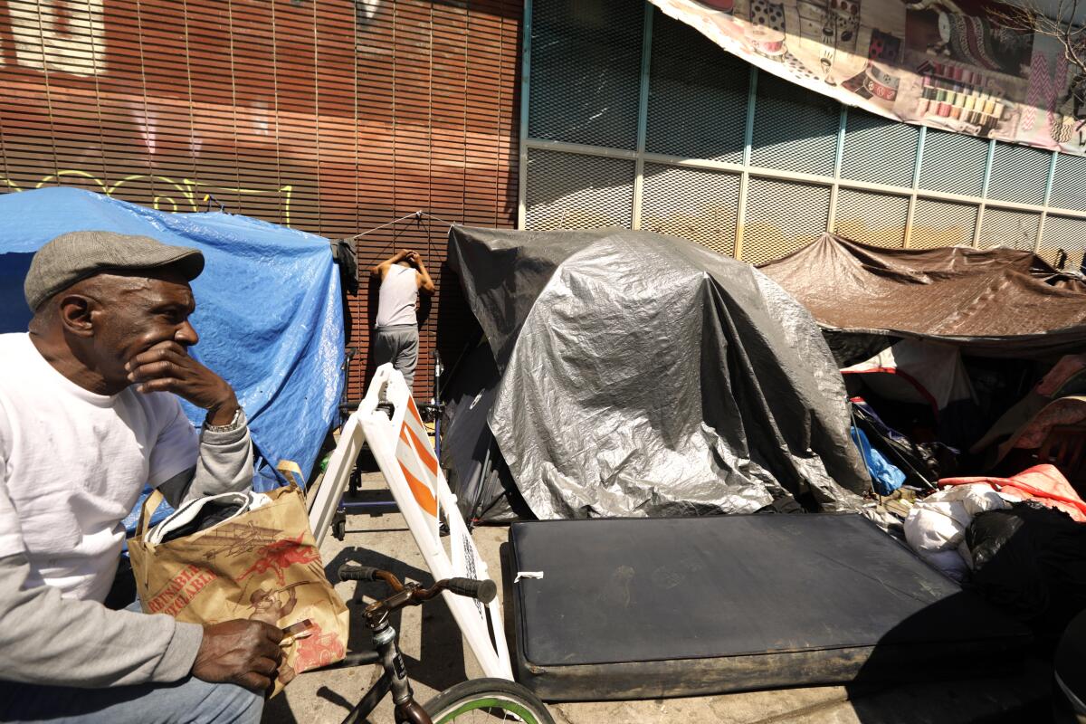 Placido Penton, left, and Jesus Delgado rest outside their encampment, where a man overdosed earlier in the day in his tent.