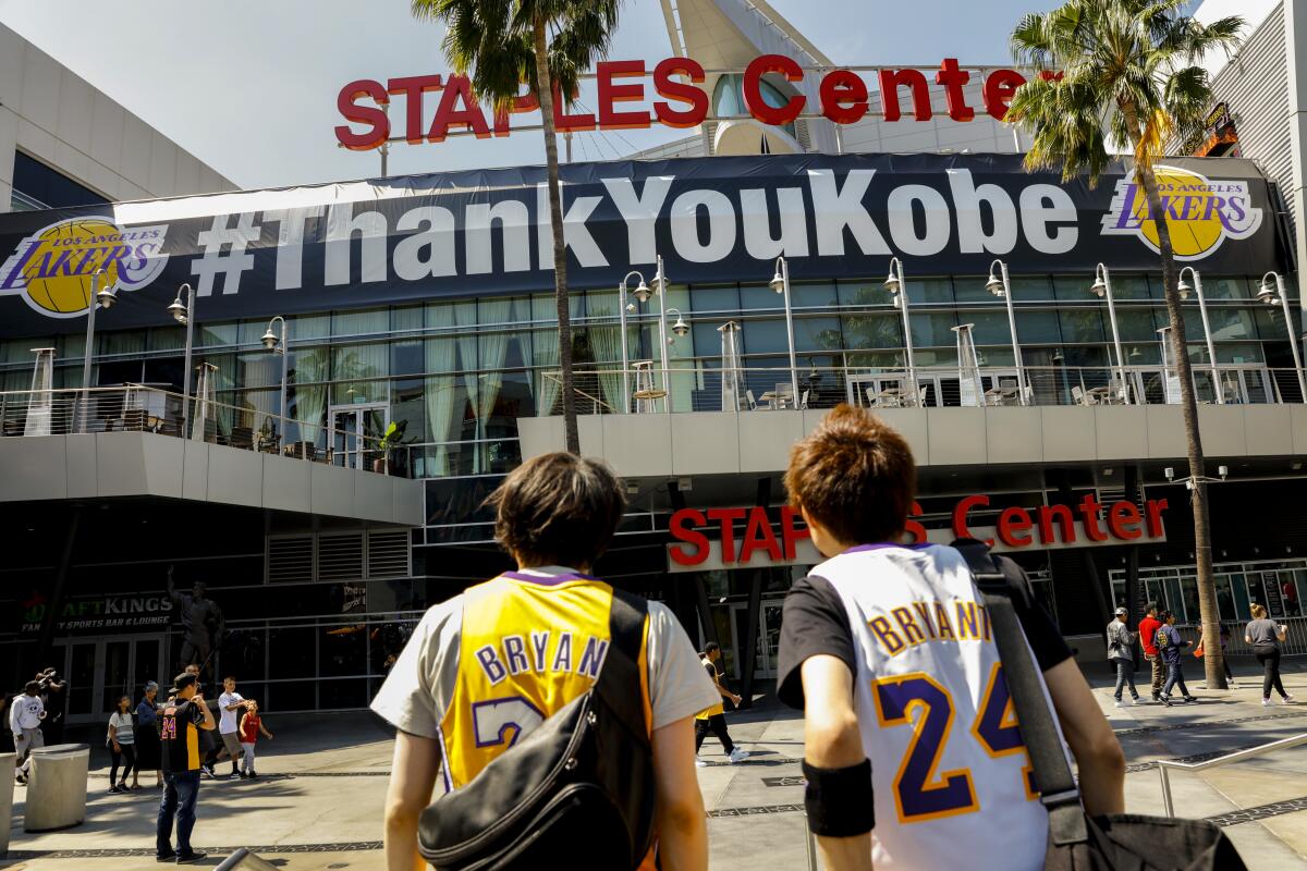 Two young fans in Kobe Bryant jerseys stand outside Staples Center