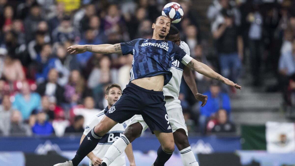 Galaxy's Zlatan Ibrahimovic, front, and Vancouver Whitecaps' Doneil Henry vie for the ball during the second half on Friday in Vancouver, Canada.