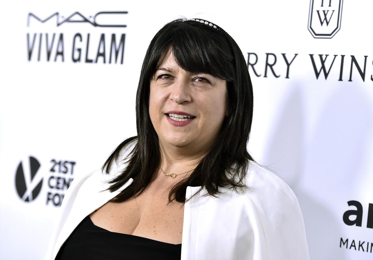 E.L. James stands in front of a wall with brand names. 