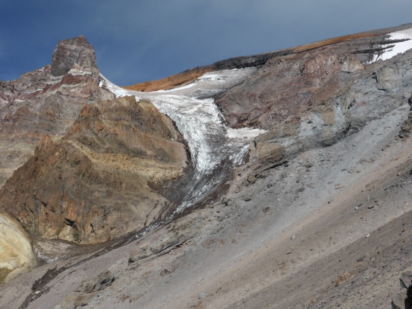 A bit of dirty-looking white ice sits in the crevice of a mountain.
