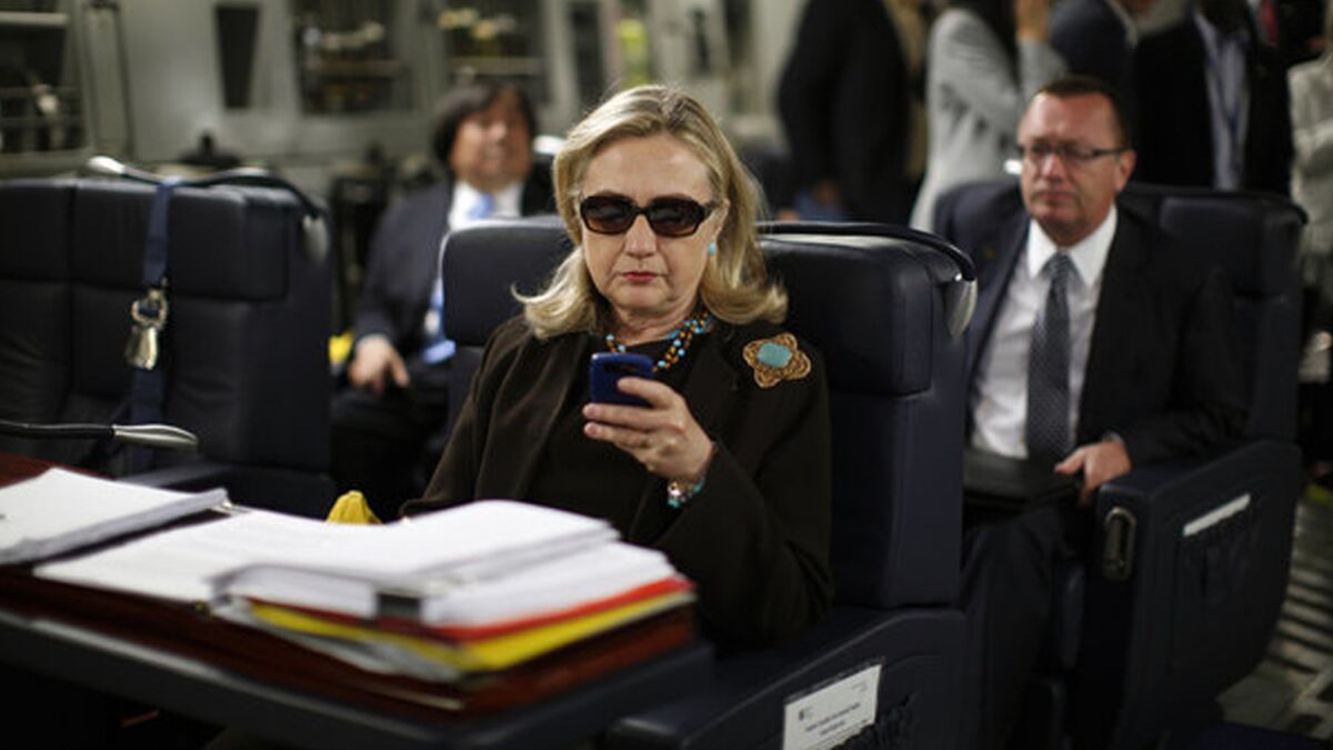 Hillary Clinton checks out her smartphone during a trip while serving as secretary of State.