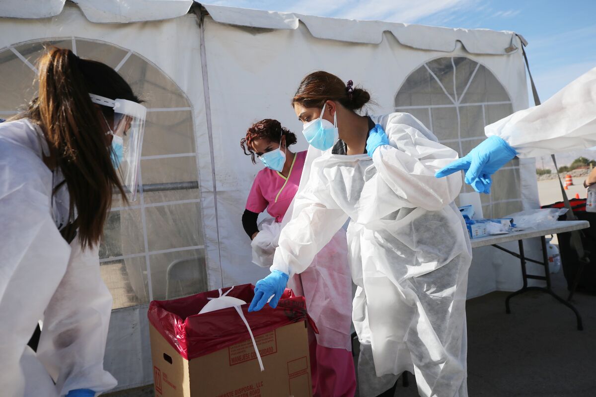 Healthcare workers decontaminate a COVID-19 testing site in El Paso on Friday. 