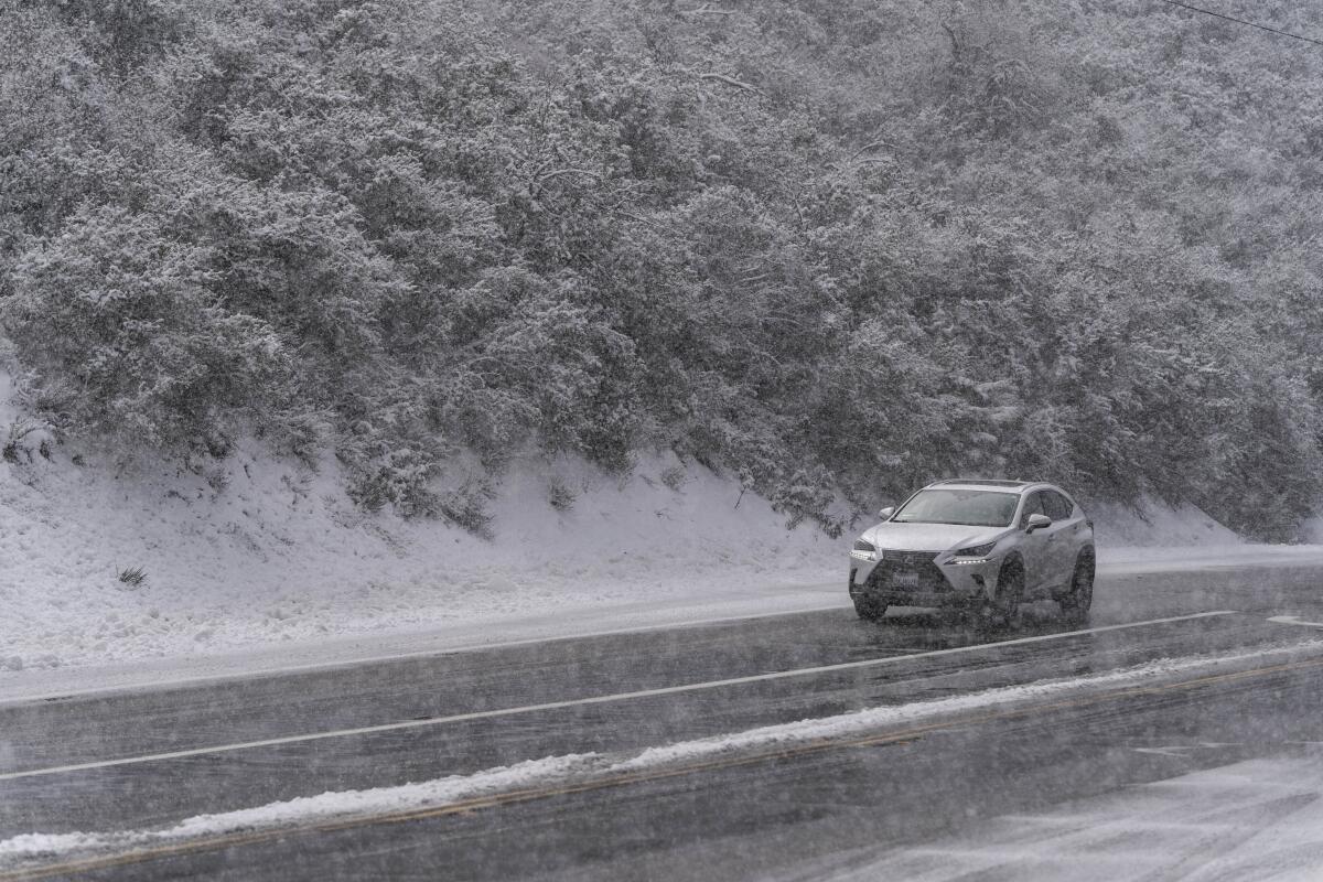 Un automovilista conduce sobre una carretera nevada en el Bosque Nacional Angeles 
