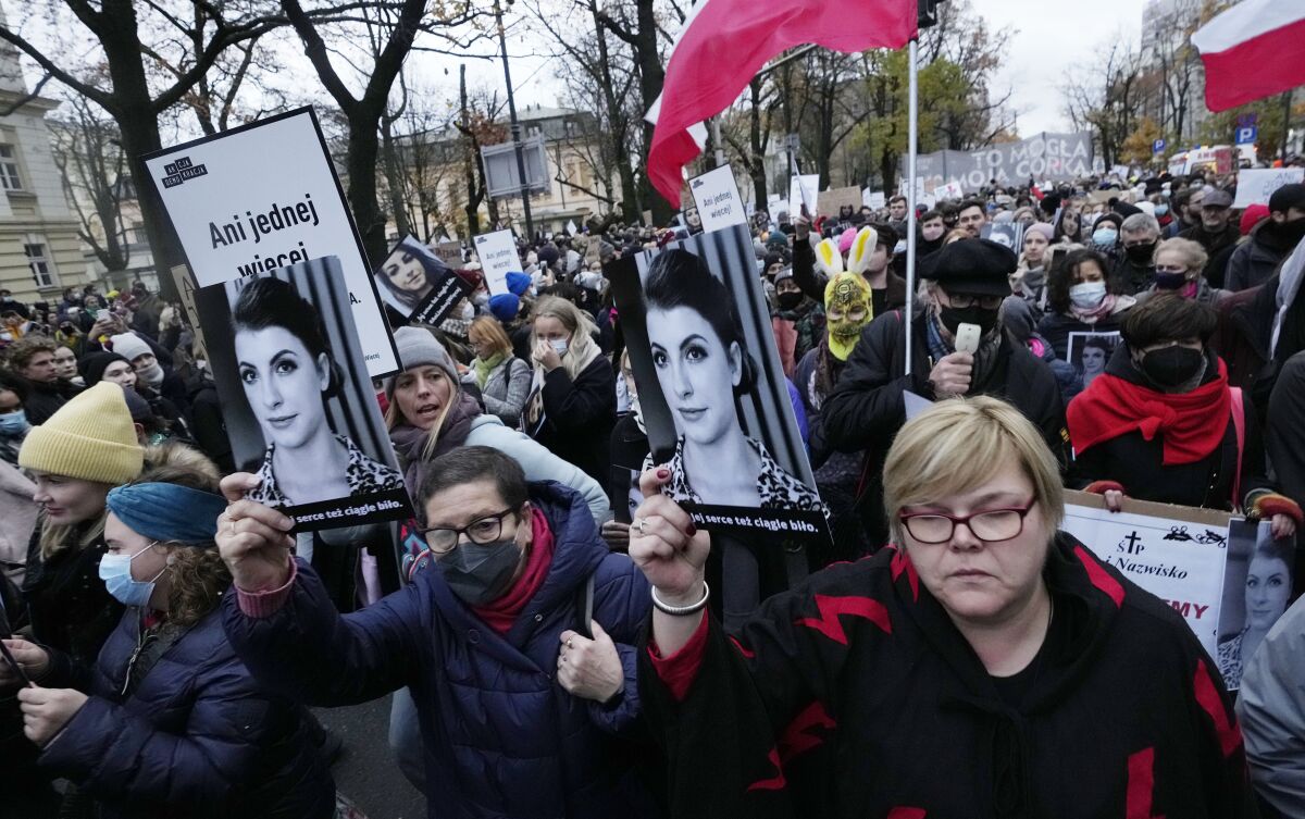 Protestors gather outside Poland's Constitutional Tribunal in Warsaw, Poland, on Saturday, Nov. 6, 2021, to protest against the restrictive abortion laws after a woman died of complications during her pregnancy. The protesters held portraits of the woman, 30-year-old Iza, who died in hospital from septic shock. Her family and a lawyer say her doctors did not terminate the pregnancy despite the fact that her fetus lacked enough amniotic fluid to survive. (AP Photo/Czarek Sokolowski)
