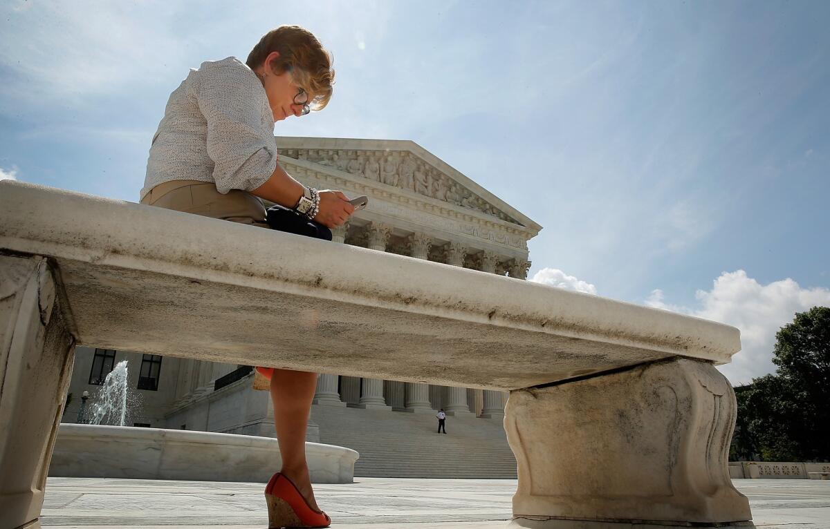 Kirsten Luna of Holland, Mich., uses her smartphone outside the U.S. Supreme Court after its ruling on cellphone privacy.