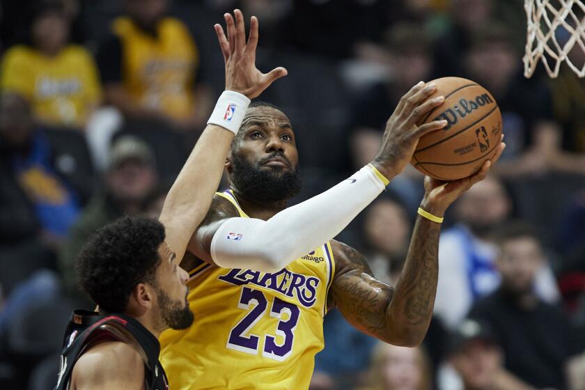 Los Angeles Lakers forward LeBron James shoots next to Portland Trail Blazers guard Skylar Mays.