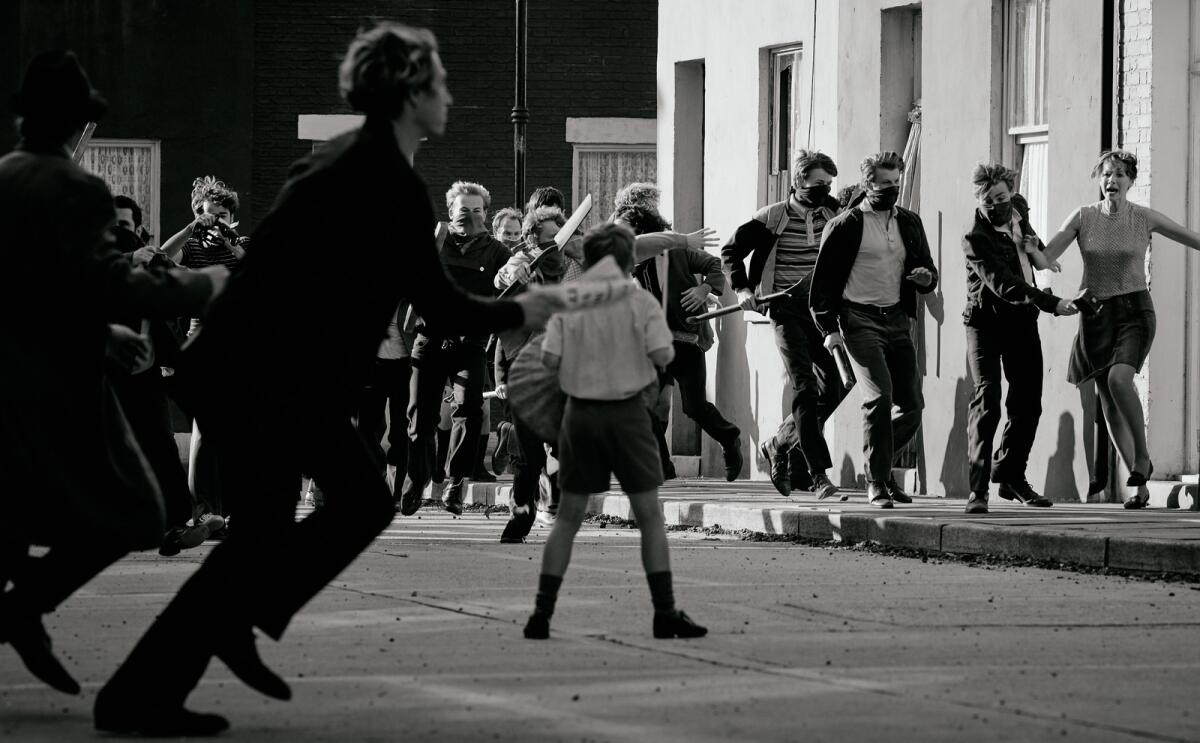 A boy is surrounded in the street by a raging mob in a scene from "Belfast."