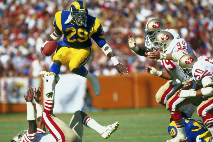 Los Angeles Rams Hall of Fame running back Eric Dickerson goes airborne to avoid the San Francisco 49ers defense.