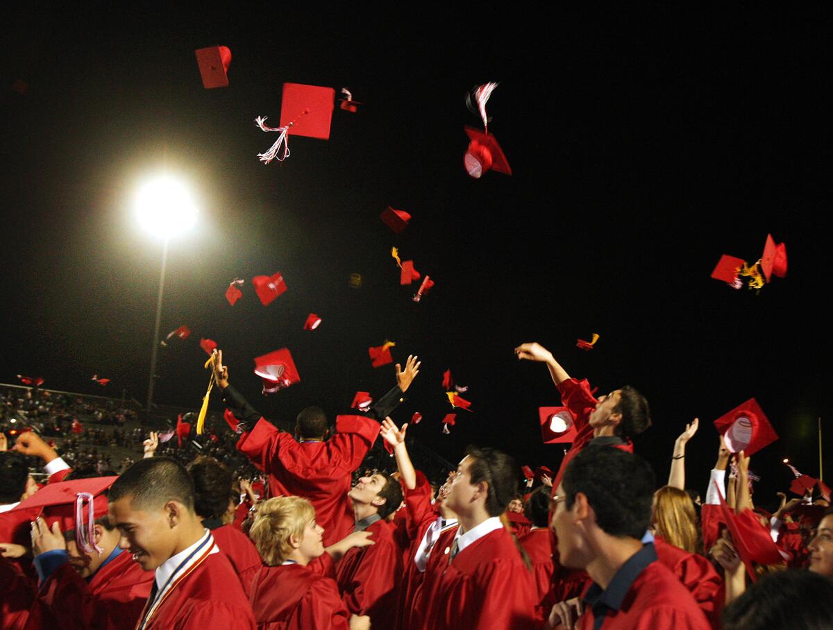 Burroughs graduates throw their caps into the air to celebrate the end of high school at the Burroughs High School graduation on Thursday, May 29, 2014.