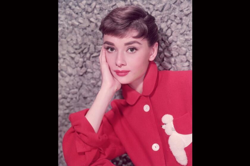 Belgian-born actor Audrey Hepburn (1929-1993) in a red jacket with a poodle applique, circa 1955.
