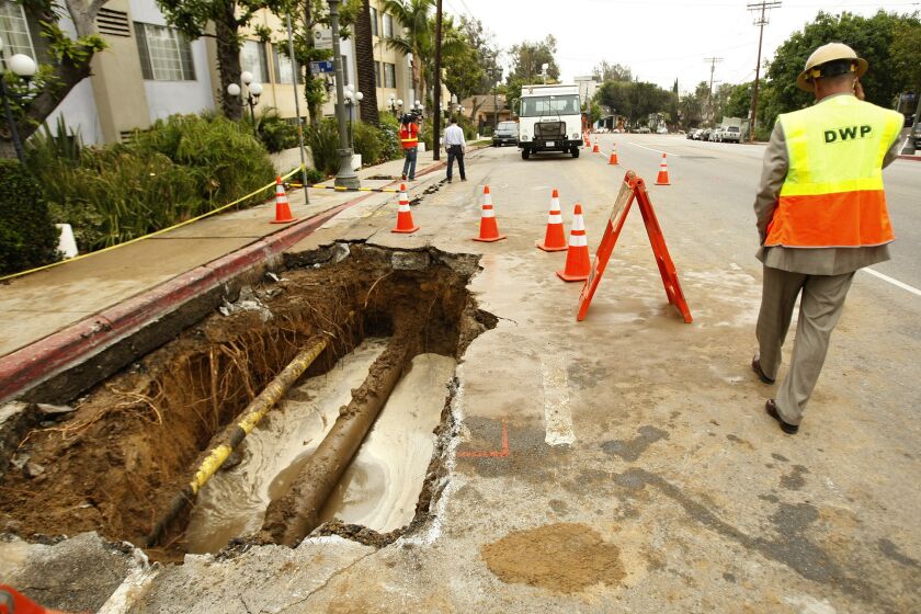 A DWP worker looks at hole created by a water main break in Hollywood.