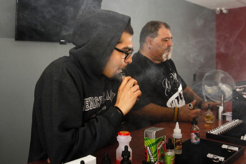 K.C. Alfred  U-T file Carlos Cardenas (left) and Jack Fontes vape e-cigarettes at Vapor Invasion in San Diego in 2015. County officials are looking for ways to address the recent spate of vaping-related illnesses.