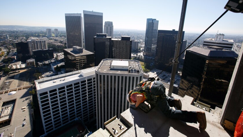 A construction worker works on a 40-floor luxury apartment building in Los Angeles this year. A housing shortage may dampen growth, say two new reports.
