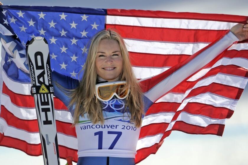 FILE -In this Feb. 20, 2010 file photo, bronze medalist Lindsey Vonn of the United States hold the Stars and Stripes during the flower ceremony for the Women's super-G at the Vancouver 2010 Olympics in Whistler, British Columbia. Vonn announced Friday, Feb. 1, 2019, that she will retire from ski racing after this month's world championships in Sweden. (AP Photo/Gero Breloer, File)