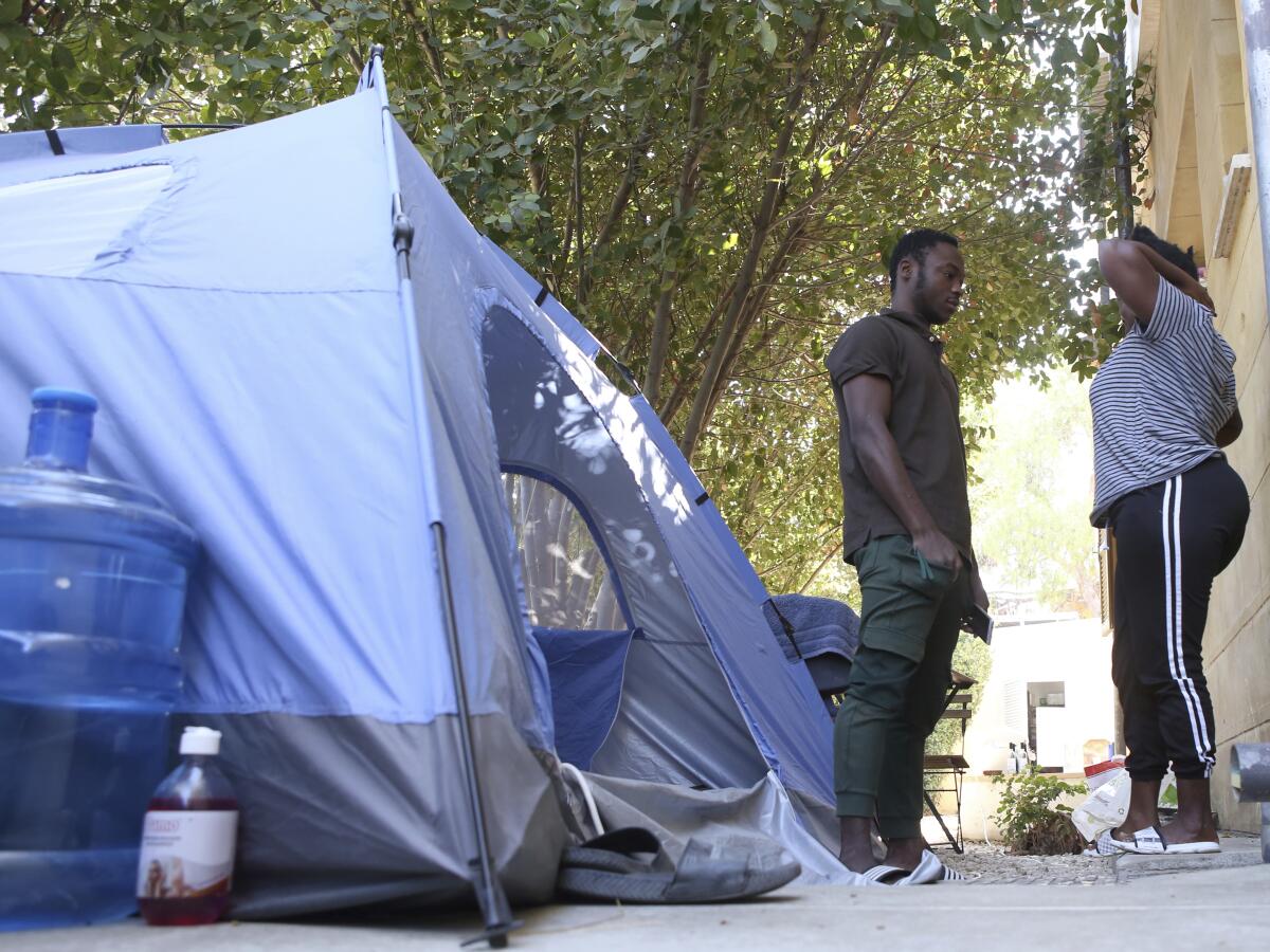 Daniel Ejube and Enjei Grace stand next to a tent.