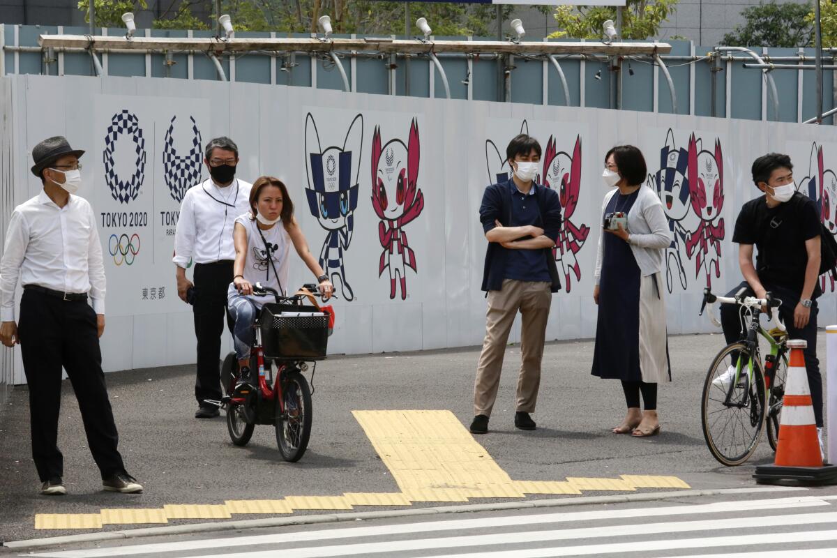 People stand by posters to promote the Tokyo Olympic Games 