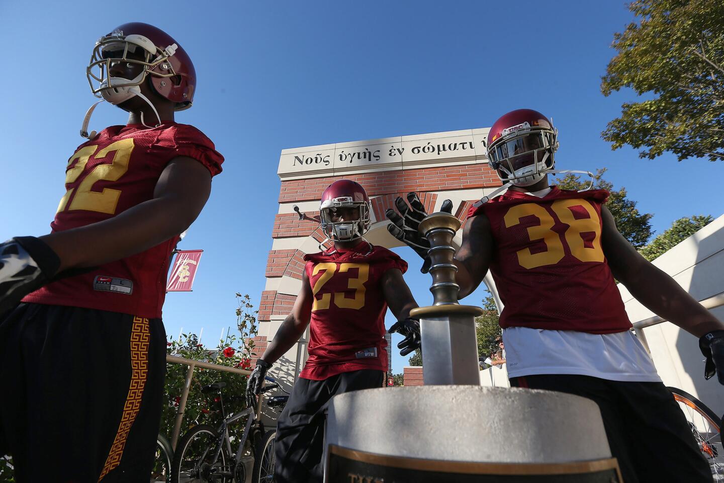 USC fullback Jahleel Pinner, right, touches a sword on the way to practice with teammates Justin Davis, left, and Tre Madden at Brian Kennedy-Howard Jones Field.