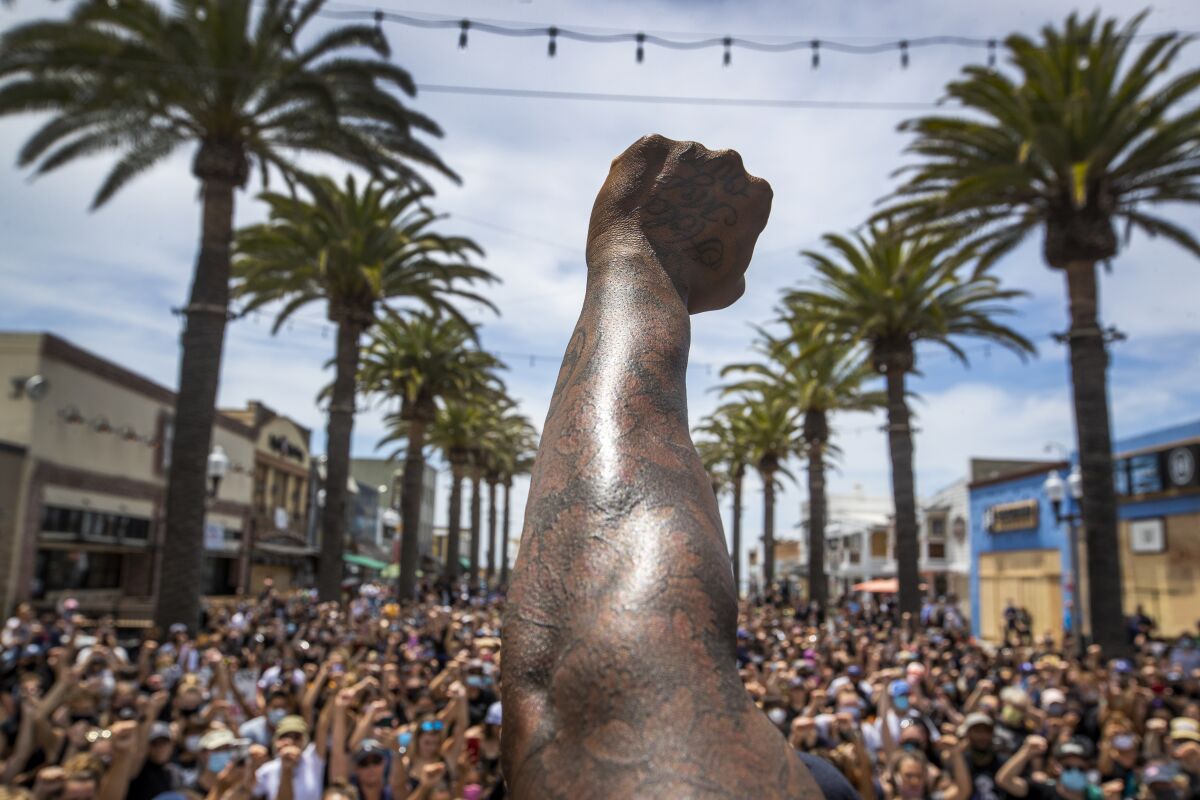 A demonstrator raises a fist at a protest at the Hermosa Beach Pier