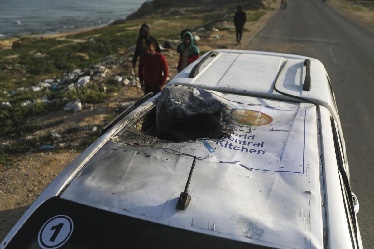 فلسطینی ها خودرویی با آرم آشپزخانه مرکزی جهانی را که در حمله هوایی اسرائیل نابود شده بود، بازرسی می کنند.